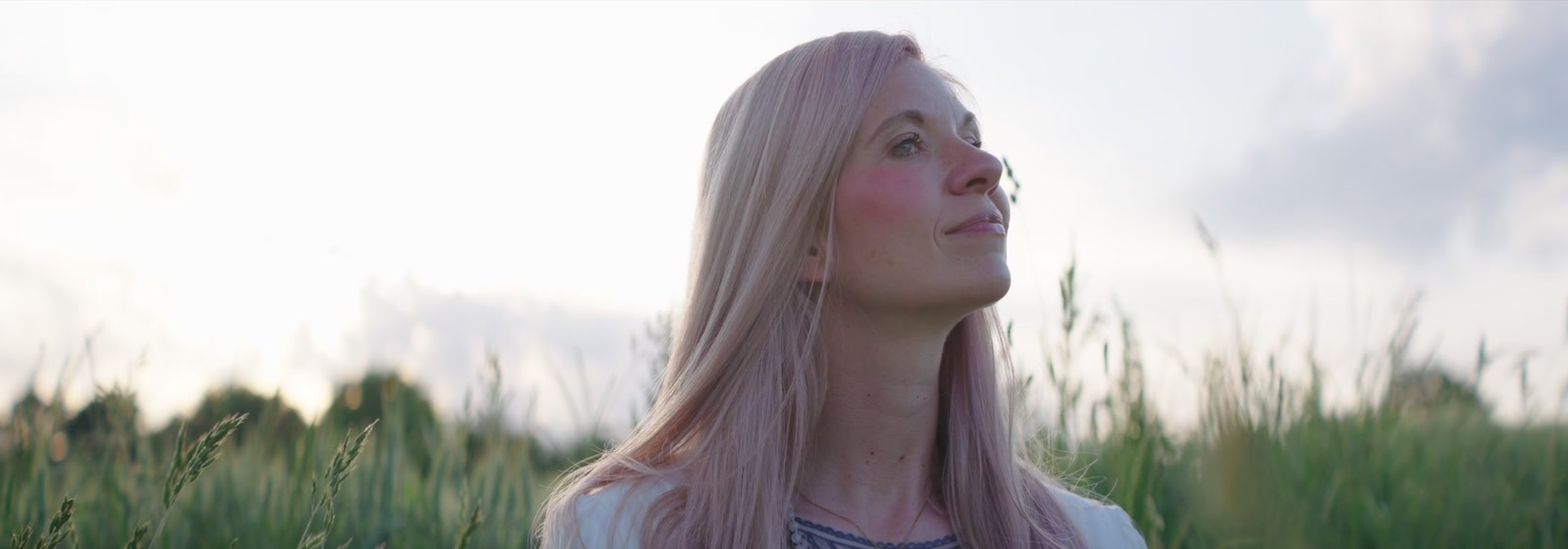Anny schaut im Gegenlicht über das Feld in den Himmel