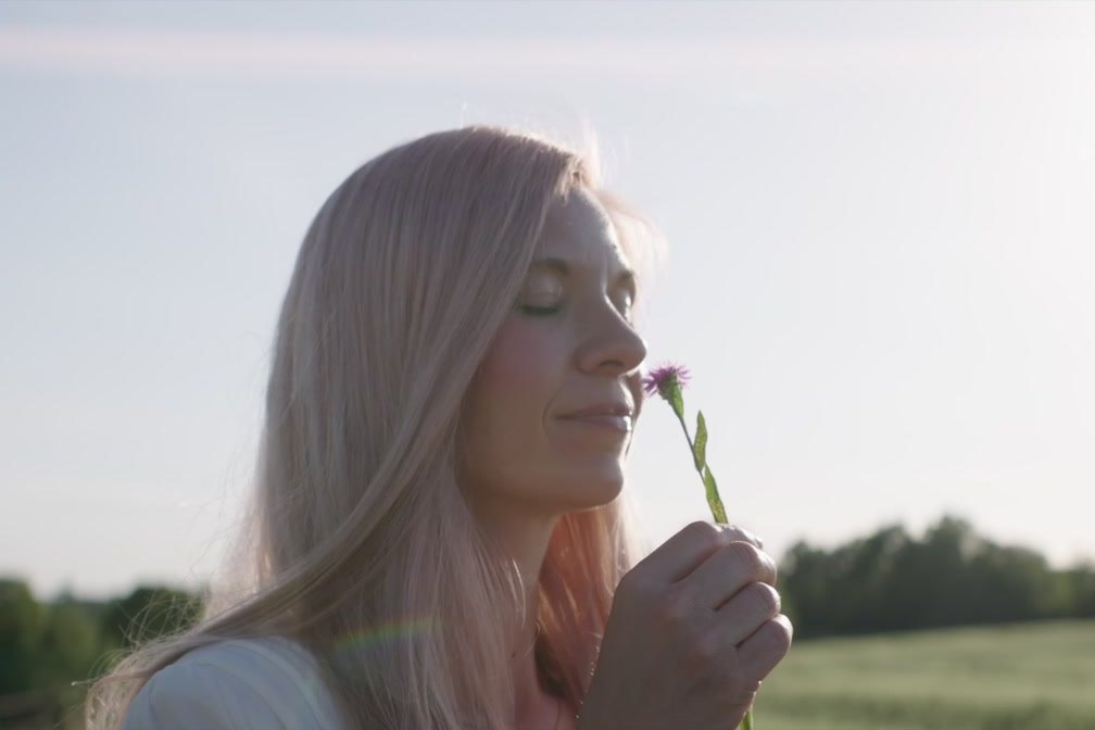Anny riecht mit geschlossenen Augen an einer Wiesenblume